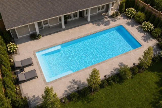 Daytime render of the Big Bob fiberglass pool with stone coping and a Caribbean Sparkle interior, seen from above at an angle.