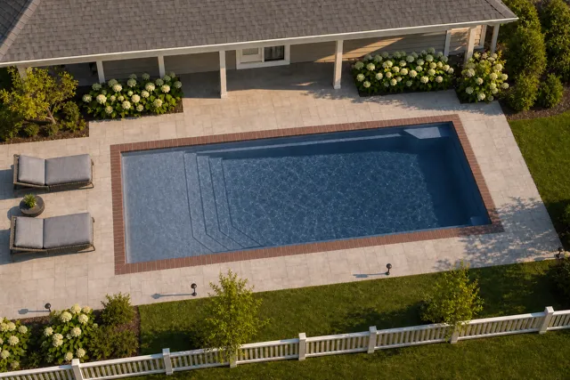 Daytime render of the Apollo 14 fiberglass pool with brick coping and a Ocean Blue interior, seen from above at an angle.
