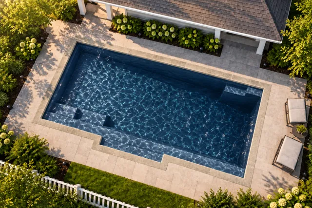 Daytime render of the Tuscan 11.20 fiberglass pool with stone coping and a Night Sky interior, seen from above at an angle.