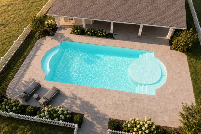 Daytime render of the Cathedral LX 1636 fiberglass pool with cantilever coping and a Arctic Shimmer interior, seen from above at an angle.