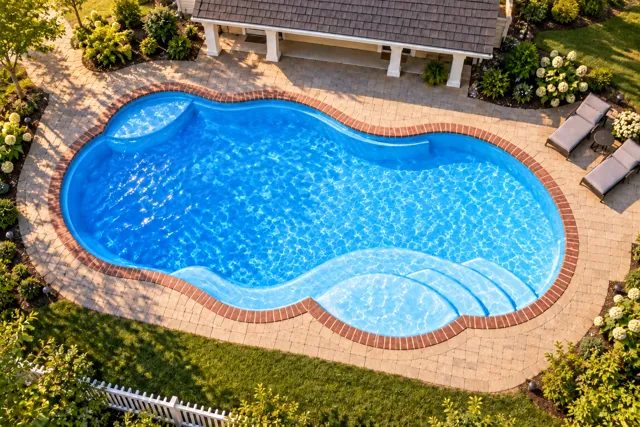 Daytime render of the Sun Day 1530 fiberglass pool with brick coping and a California interior, seen from above at an angle.