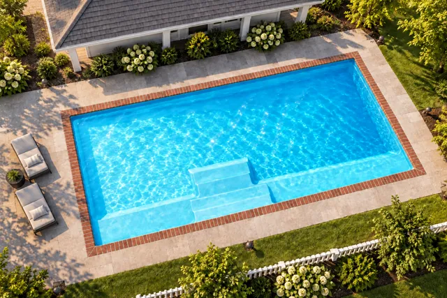 Daytime render of the The Marvelous 30 fiberglass pool with brick coping and a Coral Blue interior, seen from above at an angle.