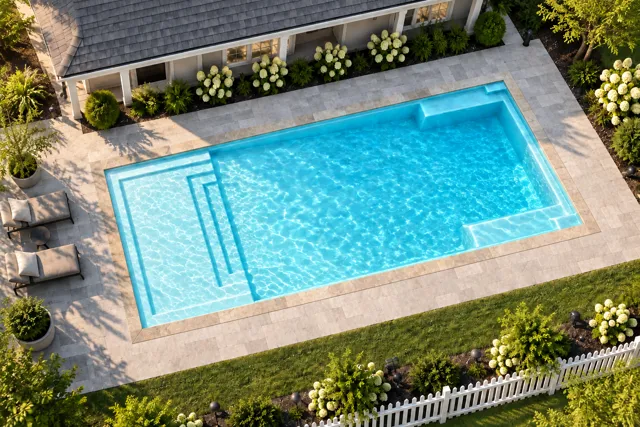 Daytime render of the The Illusion 30 fiberglass pool with stone coping and a Ice Silver interior, seen from above at an angle.