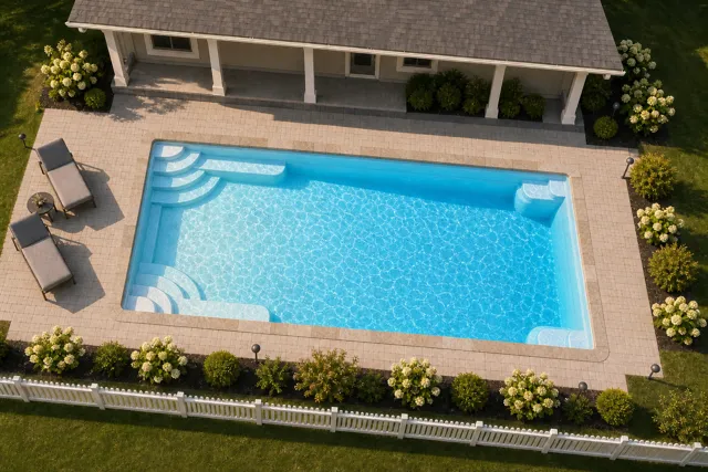 Daytime render of the Goliath 1633 fiberglass pool with stone coping and a Caribbean Sparkle interior, seen from above at an angle.
