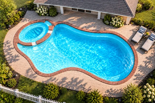 Daytime render of the The Brilliant 35 fiberglass pool with brick coping and a Coral Blue interior, seen from above at an angle.