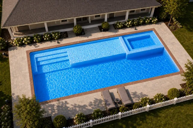 Daytime render of the Mack Daddy fiberglass pool with brick coping and a California interior, seen from above at an angle.