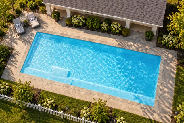 Daytime render of the The Marvelous 40 fiberglass pool with stone coping and a Ice Silver interior, seen from above at an angle.