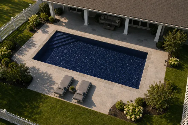 Daytime render of the Delray fiberglass pool with stone coping and a Night Sky interior, seen from above at an angle.