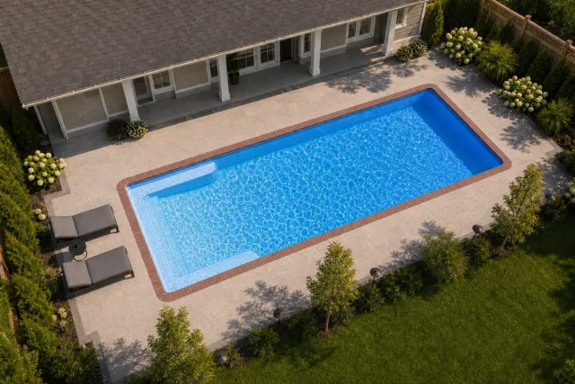 Daytime render of the Big Bob fiberglass pool with brick coping and a California interior, seen from above at an angle.