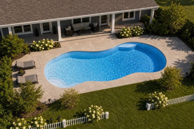 Daytime render of the Bay Isle fiberglass pool with cantilever coping and a Sapphire Blue interior, seen from above at an angle.