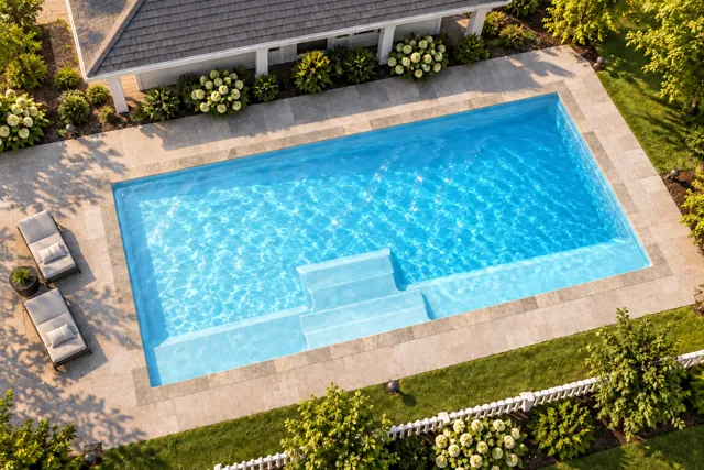 Daytime render of the The Marvelous 30 fiberglass pool with stone coping and a Ice Silver interior, seen from above at an angle.