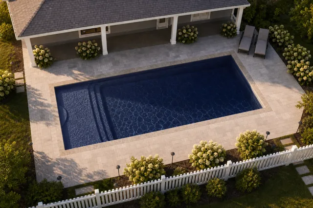 Daytime render of the Cayman 14 fiberglass pool with stone coping and a Night Sky interior, seen from above at an angle.