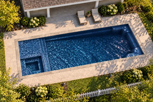 Daytime render of the Astoria 14 fiberglass pool with stone coping and a Night Sky interior, seen from above at an angle.