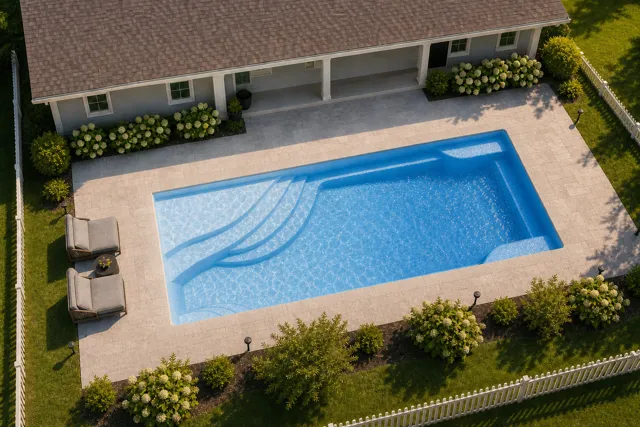 Daytime render of the Olympia 14 fiberglass pool with cantilever coping and a Sapphire Blue interior, seen from above at an angle.