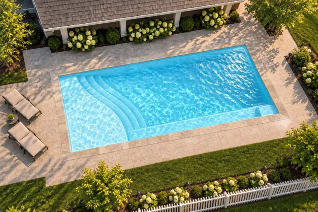 Daytime render of the The Bliss 35 fiberglass pool with stone coping and a Ice Silver interior, seen from above at an angle.