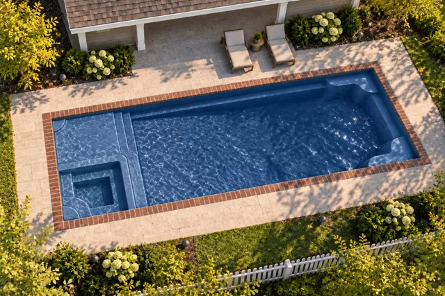 Daytime render of the Astoria 14 fiberglass pool with brick coping and a Ocean Blue interior, seen from above at an angle.