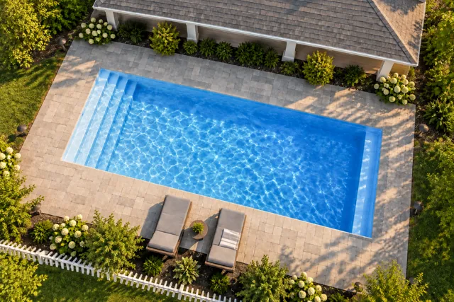 Daytime render of the Kingston fiberglass pool with cantilever coping and a Sapphire Blue interior, seen from above at an angle.