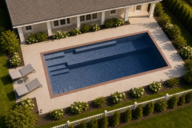 Daytime render of the Providence 14 fiberglass pool with brick coping and a Ocean Blue interior, seen from above at an angle.