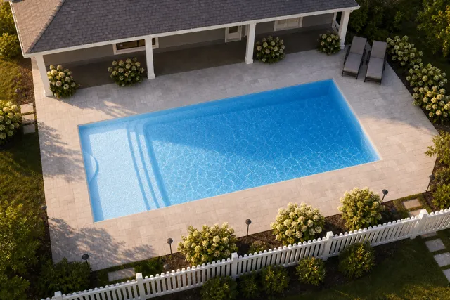 Daytime render of the Cayman 14 fiberglass pool with cantilever coping and a Sapphire Blue interior, seen from above at an angle.