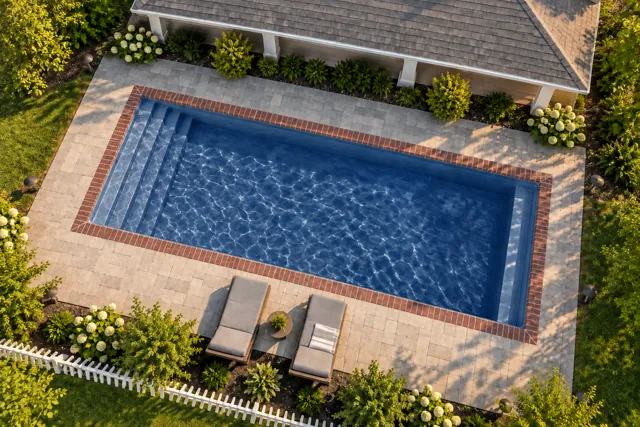 Daytime render of the Kingston fiberglass pool with brick coping and a Ocean Blue interior, seen from above at an angle.