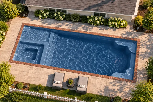 Daytime render of the Astoria 12 fiberglass pool with brick coping and a Ocean Blue interior, seen from above at an angle.