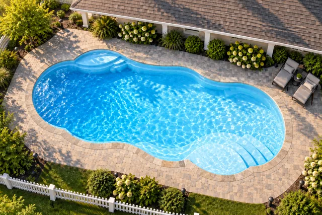 Daytime render of the Sun Day 1639 fiberglass pool with stone coping and a Caribbean Sparkle interior, seen from above at an angle.