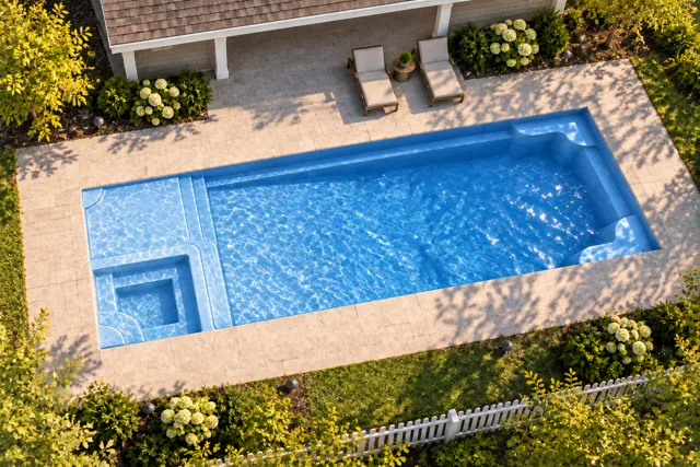 Daytime render of the Astoria 14 fiberglass pool with cantilever coping and a Sapphire Blue interior, seen from above at an angle.
