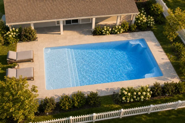 Daytime render of the Corinthian 14 fiberglass pool with cantilever coping and a Sapphire Blue interior, seen from above at an angle.