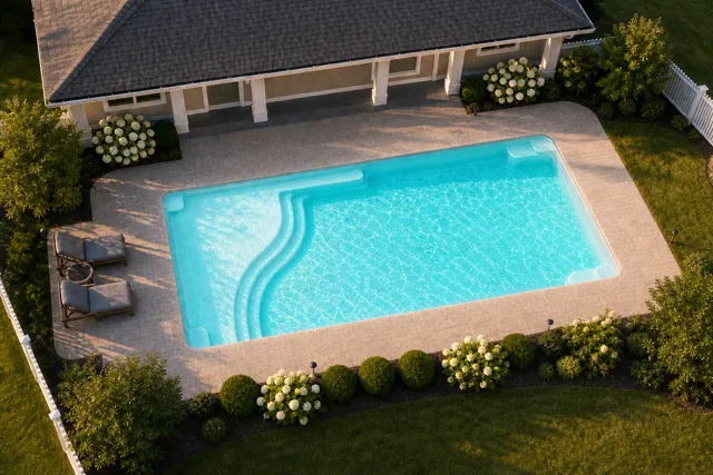 Daytime render of the Aspen 1635 fiberglass pool with cantilever coping and a Arctic Shimmer interior, seen from above at an angle.