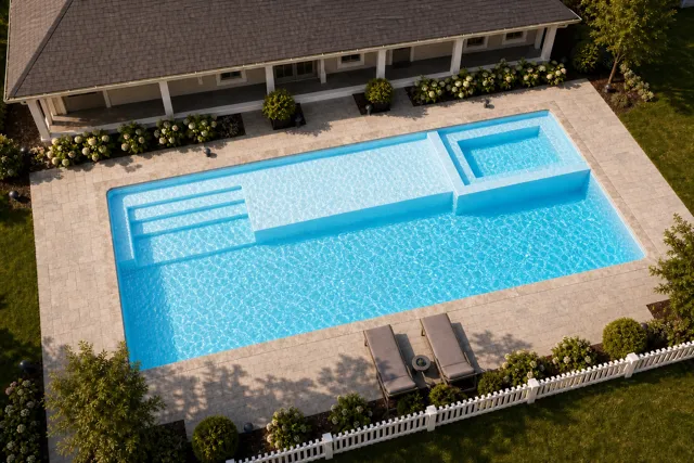 Daytime render of the Mack Daddy fiberglass pool with stone coping and a Caribbean Sparkle interior, seen from above at an angle.