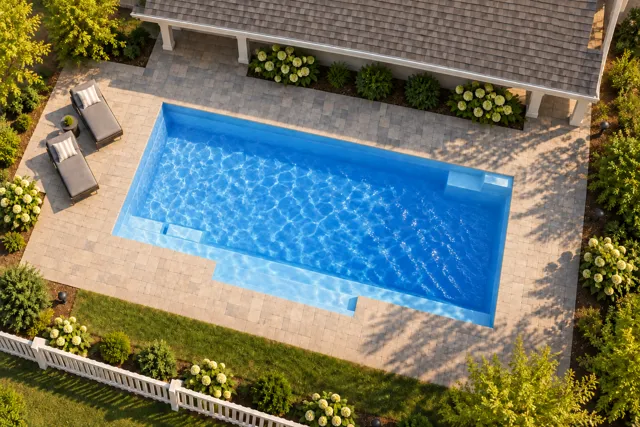 Daytime render of the Tuscan 14.27 fiberglass pool with cantilever coping and a Sapphire Blue interior, seen from above at an angle.
