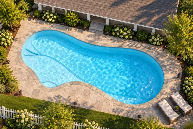 Daytime render of the The Inspiration 35 fiberglass pool with stone coping and a Ice Silver interior, seen from above at an angle.