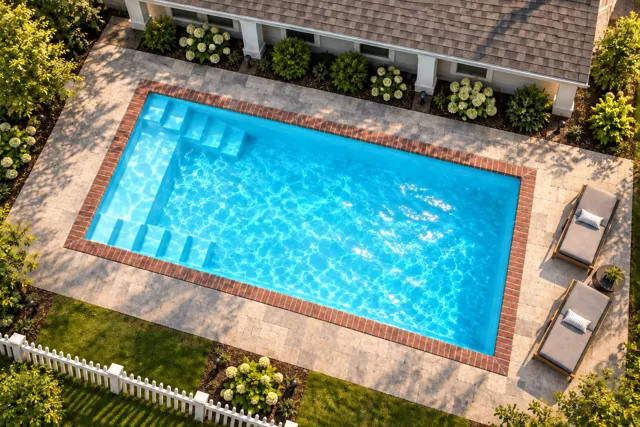 Daytime render of the The Freedom 23 fiberglass pool with brick coping and a Coral Blue interior, seen from above at an angle.