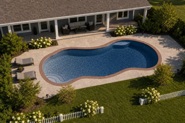 Daytime render of the Bay Isle fiberglass pool with brick coping and a Ocean Blue interior, seen from above at an angle.