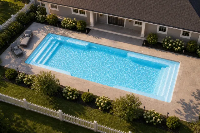 Daytime render of the Spirit fiberglass pool with stone coping and a Caribbean Sparkle interior, seen from above at an angle.