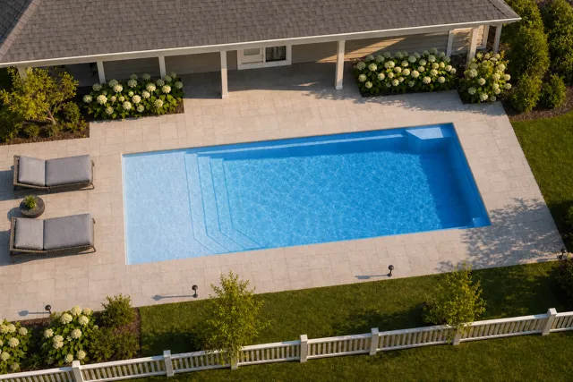 Daytime render of the Apollo 14 fiberglass pool with cantilever coping and a Sapphire Blue interior, seen from above at an angle.