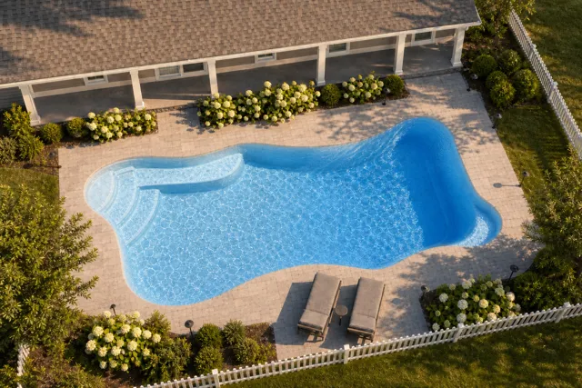 Daytime render of the Cape Cod 12 fiberglass pool with cantilever coping and a Sapphire Blue interior, seen from above at an angle.