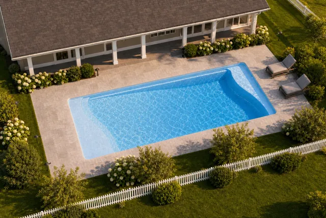 Daytime render of the Barcelona fiberglass pool with cantilever coping and a Sapphire Blue interior, seen from above at an angle.