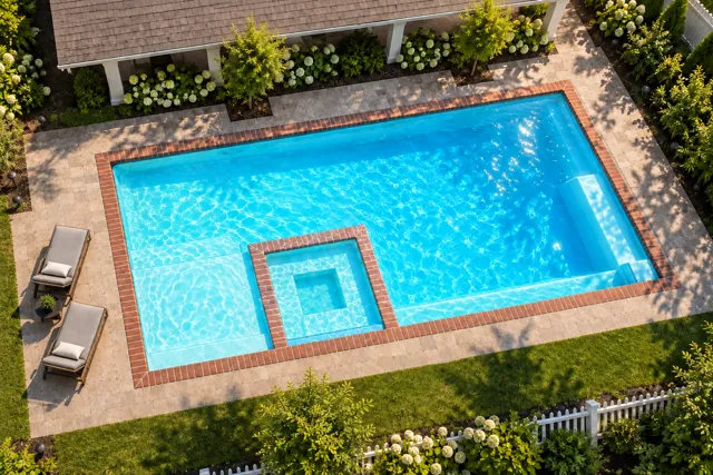 Daytime render of the The Exquisite 30 fiberglass pool with brick coping and a Coral Blue interior, seen from above at an angle.