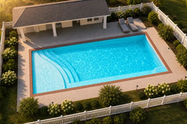 Daytime render of the The Bliss 26 fiberglass pool with brick coping and a Coral Blue interior, seen from above at an angle.