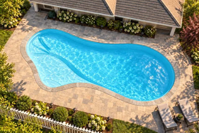 Daytime render of the The Inspiration 26 fiberglass pool with stone coping and a Ice Silver interior, seen from above at an angle.