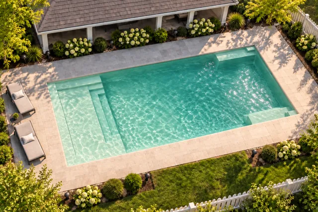 Daytime render of the The Illusion 35 fiberglass pool with cantilever coping and a Beach Sand interior, seen from above at an angle.