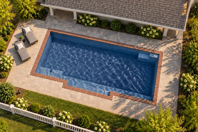 Daytime render of the Tuscan 14.27 fiberglass pool with brick coping and a Ocean Blue interior, seen from above at an angle.