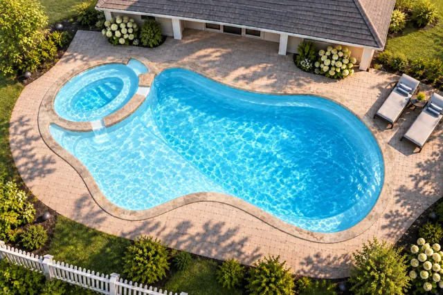 Daytime render of the The Brilliant 35 fiberglass pool with stone coping and a Ice Silver interior, seen from above at an angle.