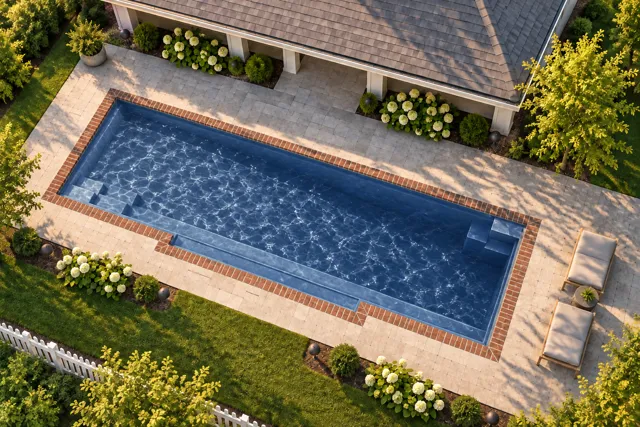 Daytime render of the Tuscan 14.40 fiberglass pool with brick coping and a Ocean Blue interior, seen from above at an angle.