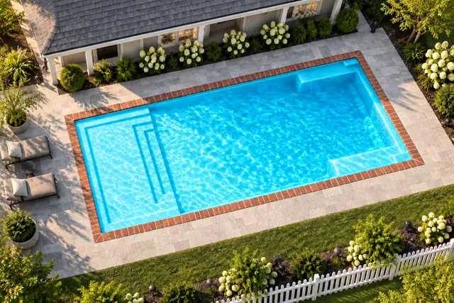 Daytime render of the The Illusion 30 fiberglass pool with brick coping and a Coral Blue interior, seen from above at an angle.