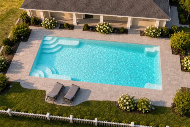 Daytime render of the Goliath 1433 fiberglass pool with cantilever coping and a Arctic Shimmer interior, seen from above at an angle.