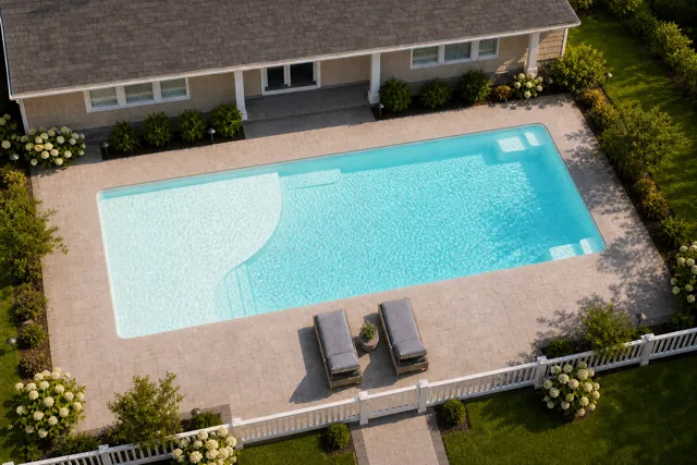 Daytime render of the Grace Beach Entry 1436 fiberglass pool with cantilever coping and a Arctic Shimmer interior, seen from above at an angle.