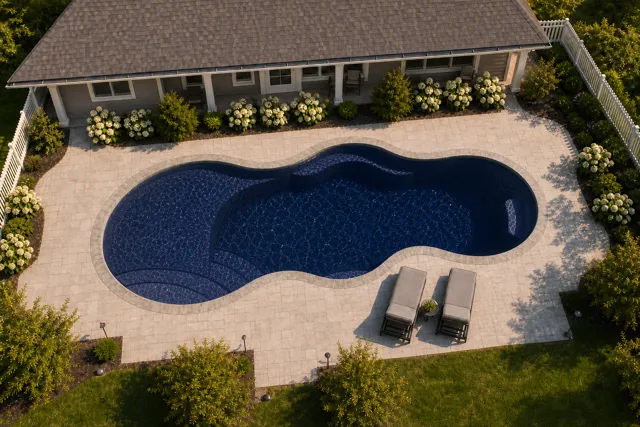 Daytime render of the Axiom 12 fiberglass pool with stone coping and a Night Sky interior, seen from above at an angle.