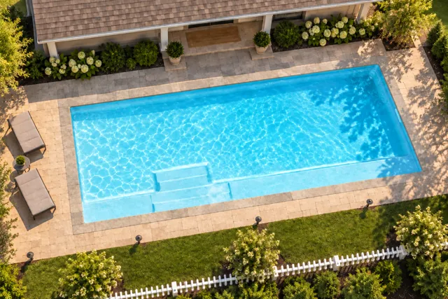 Daytime render of the The Marvelous 35 fiberglass pool with stone coping and a Ice Silver interior, seen from above at an angle.
